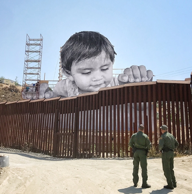Un niño gigante se asoma a la frontera entre México y EE.UU